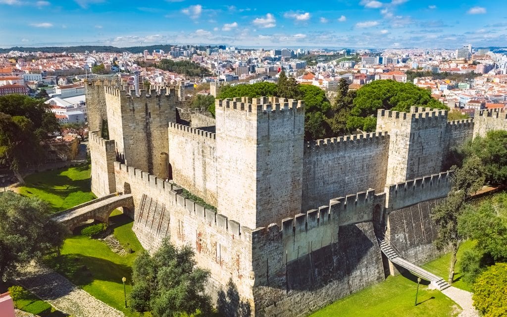 Castelo de São Jorge em Lisboa com altas muralhas de pedra, torreões quadrados e vista ampla para a cidade ao redor, ótimo passeio para adolescentes conhecerem a história da cidade e tirar fotos | 10 melhores passeios para adolescentes em Lisboa #8
