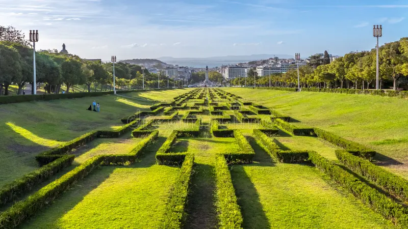 Parque Eduardo VII visto de cima com grandes áreas verdes gramadas, um caminho central alinhado em direção ao rio Tejo ao fundo e espaço aberto para piqueniques e passeios de adolescentes em Lisboa | 10 melhores passeios para adolescentes em Lisboa #10